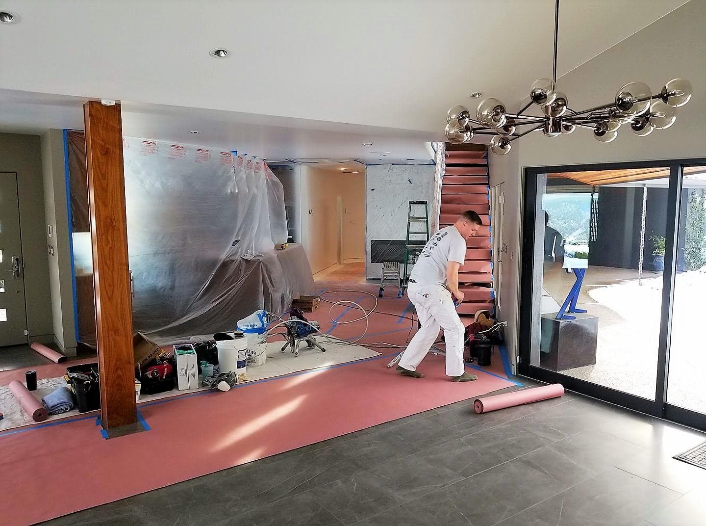 Painter working inside a home with floors and fixtures masked for protection